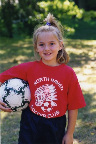 Samantha Tabak as a young girl, with soccer ball tucked under her arm.