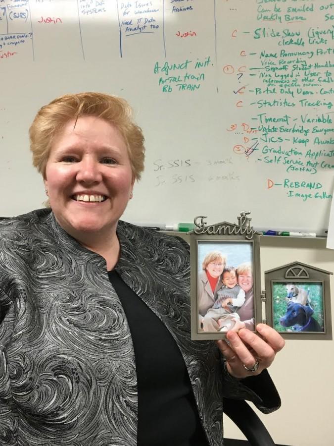 AIC Chief Information Officer Mimi Royston holding a photo of herself with her late wife Monica Harlow Royston and their son Morgan, who is now 11.