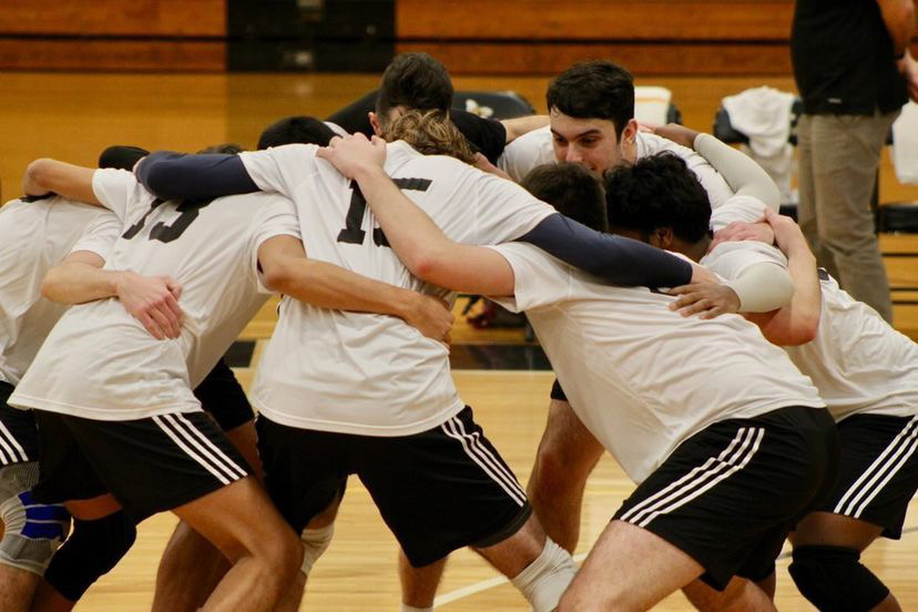 The mens volleyball team huddles before play.